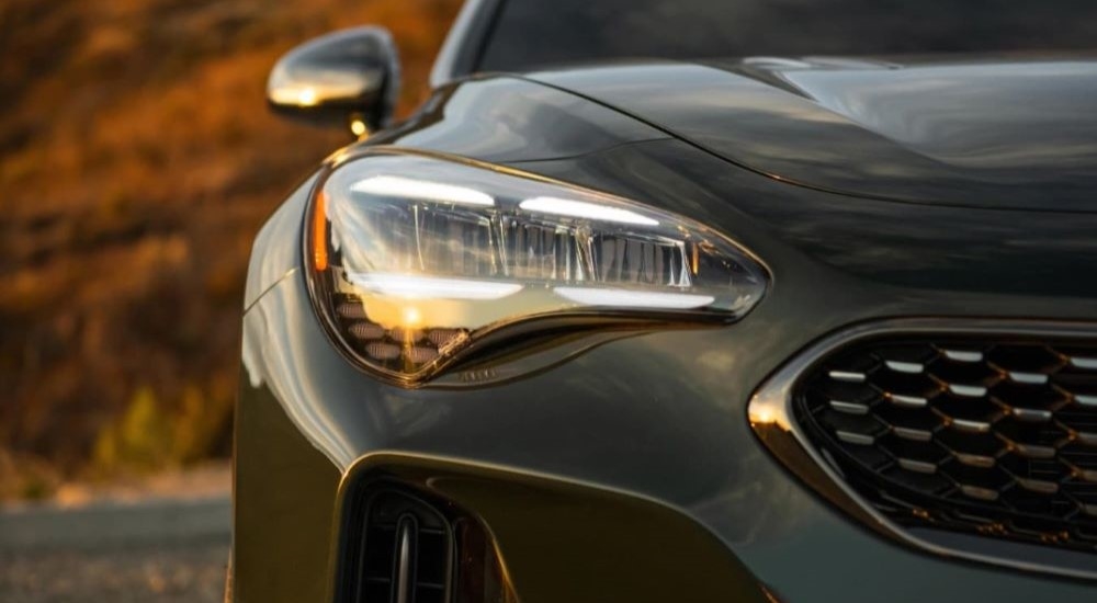 A close up of the headlight on a green 2023 Kia Stinger.