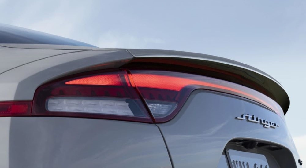 A close up of the trunk and tail lights on a silver 2023 Kia Stinger at a Kia dealer near Corpus Christi.