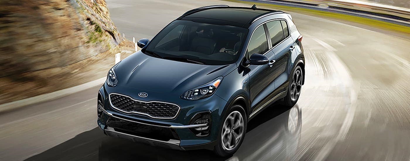 A blue 2020 Kia Sportage is shown rounding a corner.