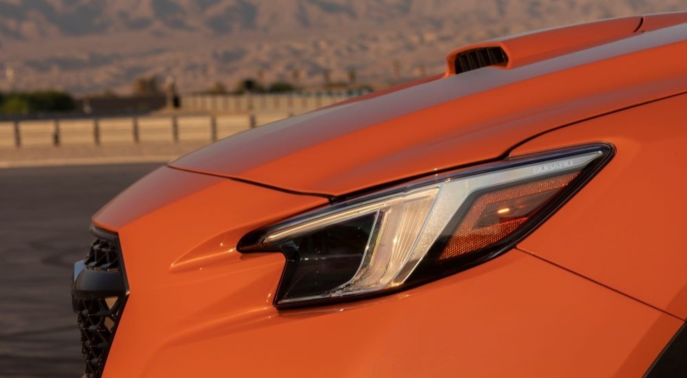A close up shows the drive side headlight on an orange 2022 Subaru WRX.