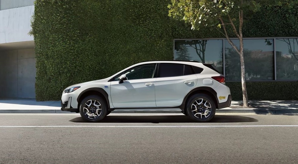 A white 2023 Subaru Crosstrek Hybrid is shown from the side on a city street.