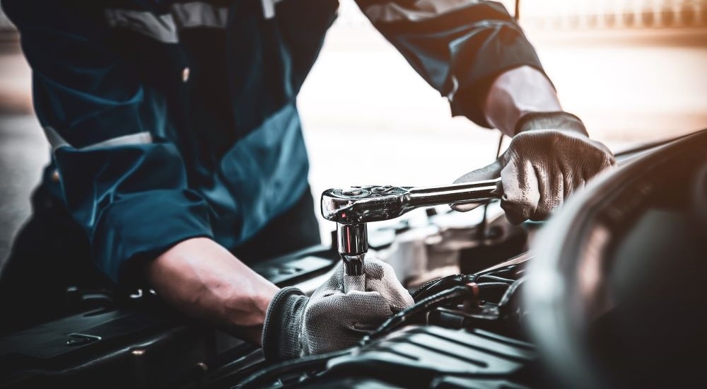 Close up of a mechanic using a socket wrench on an engine.