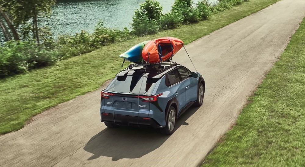 A blue 2023 Subaru Solterra is shown driving near a river.