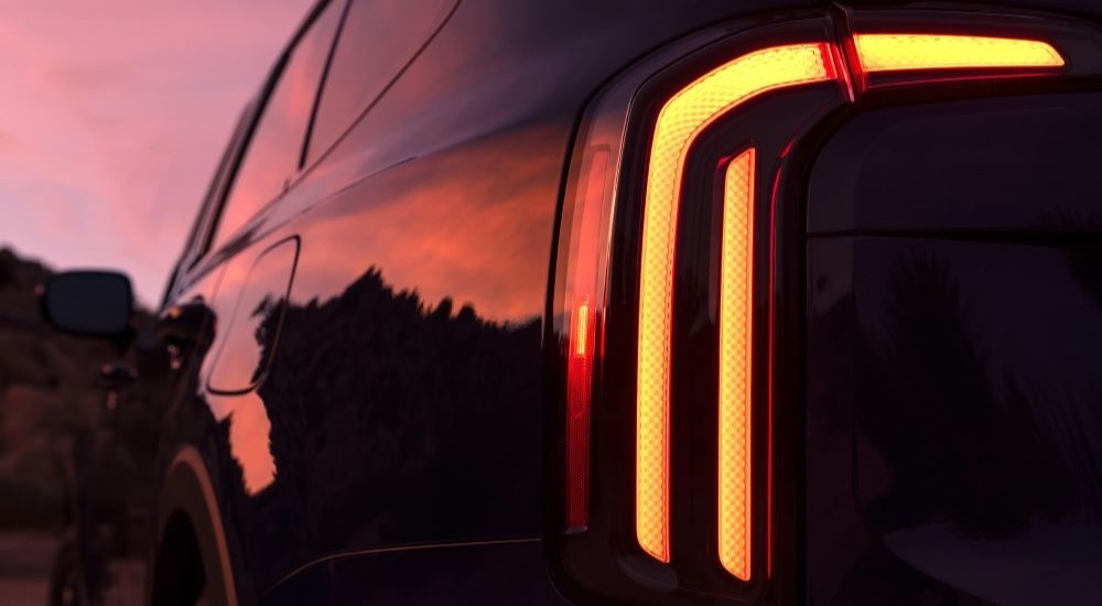 A close up of the driver side taillight on a black 2024 Kia Telluride at sunset.
