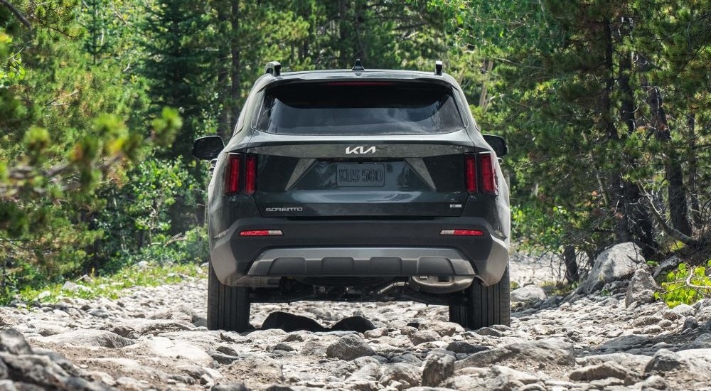 A green 2022 Kia Sorento X-Line off-roading on a rocky path.