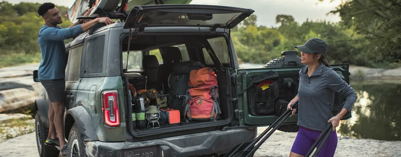 People are shown removing kayaking equipment from a grey 2023 Ford Bronco.