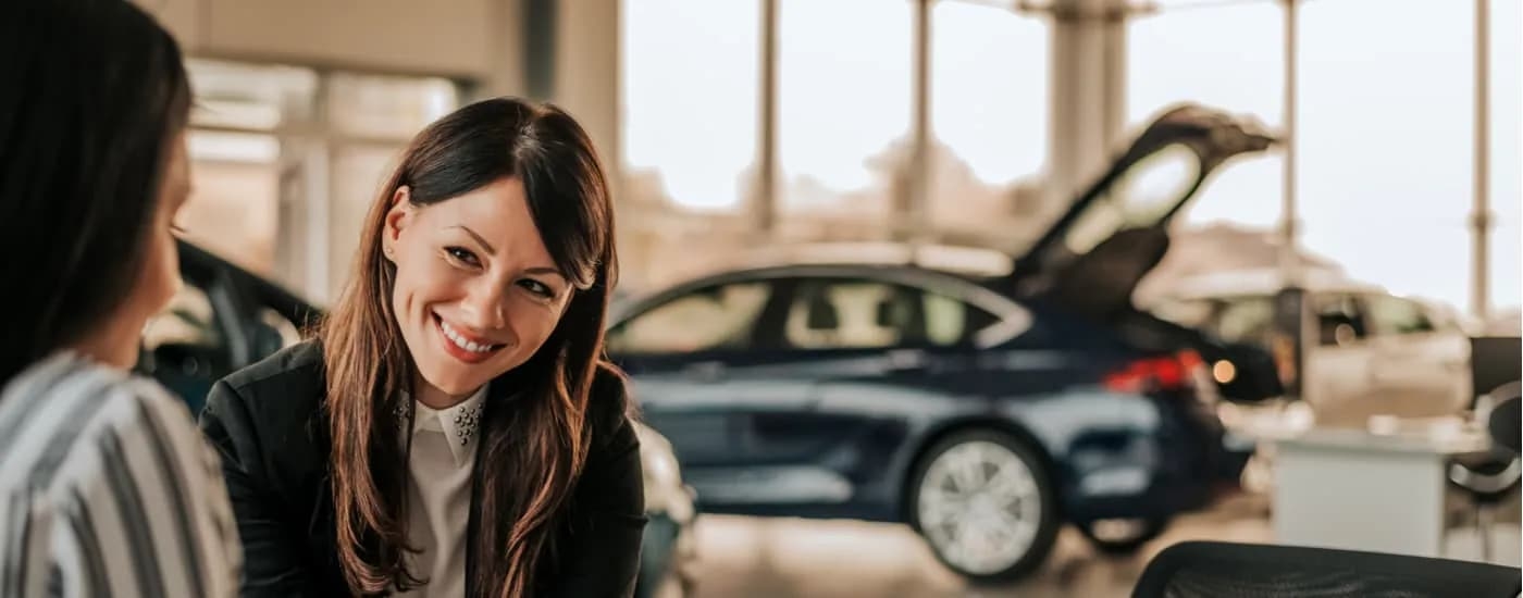 A saleswoman is shown speaking to a customer at a Ford dealer.