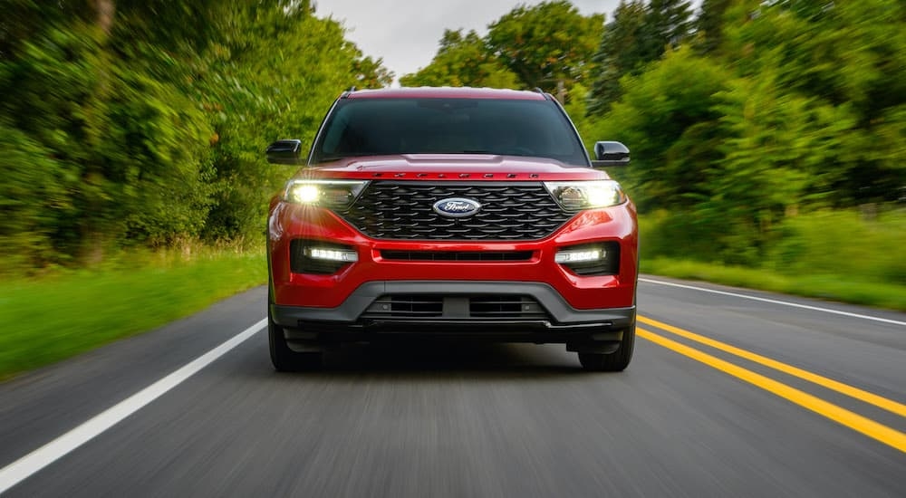A red 2022 Ford Explorer ST-Line is shown from the front driving on an empty road after leaving a Ford dealership.