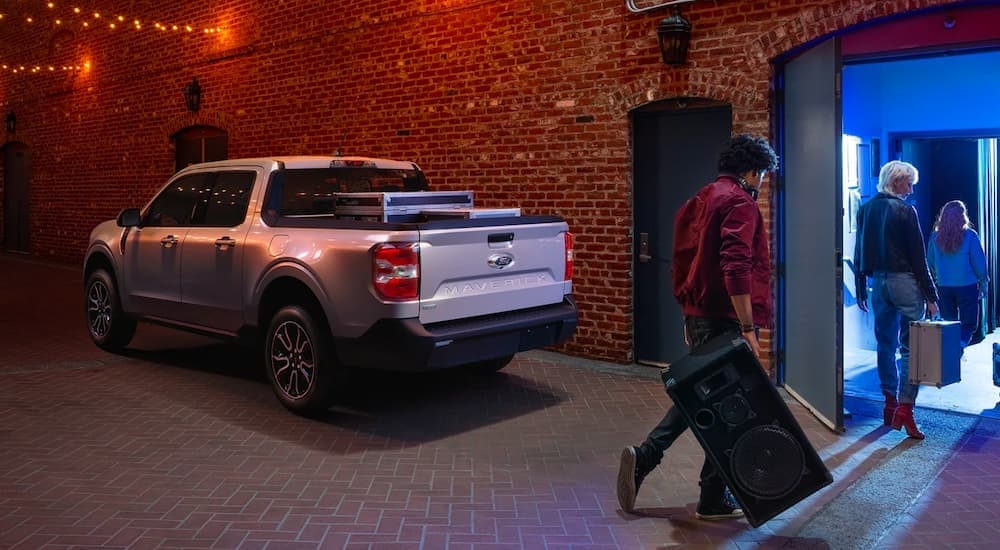 A silver 2022 Ford Maverick is shown from the rear at a music venue.