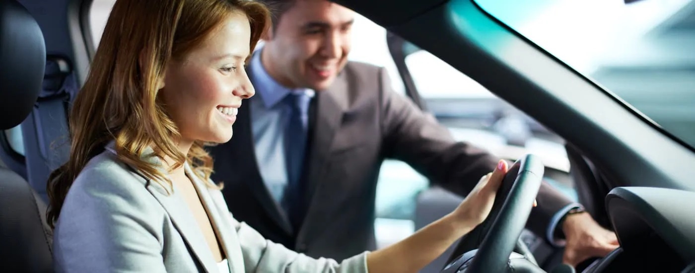 A woman is shown sitting in the front seat of a car at a Ford dealer near you.