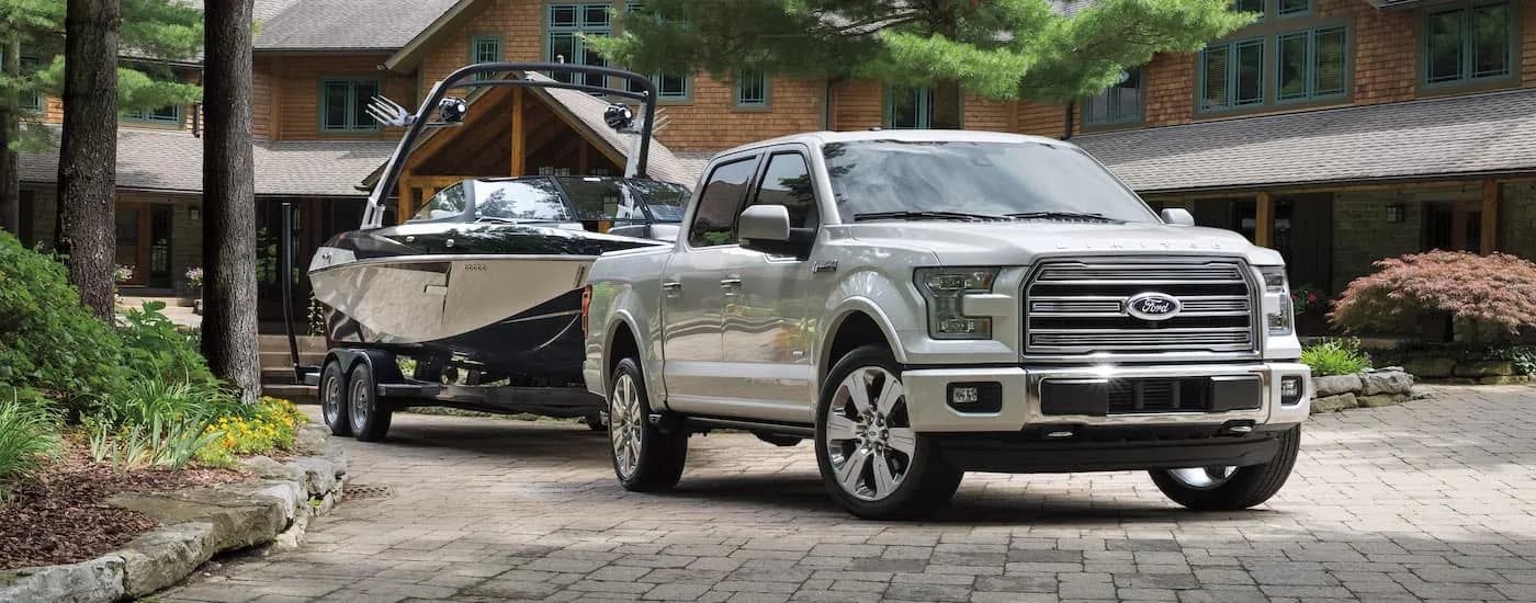 A white 2016 Ford F-150 Limited is shown attached to a boat, parked in a driveway.