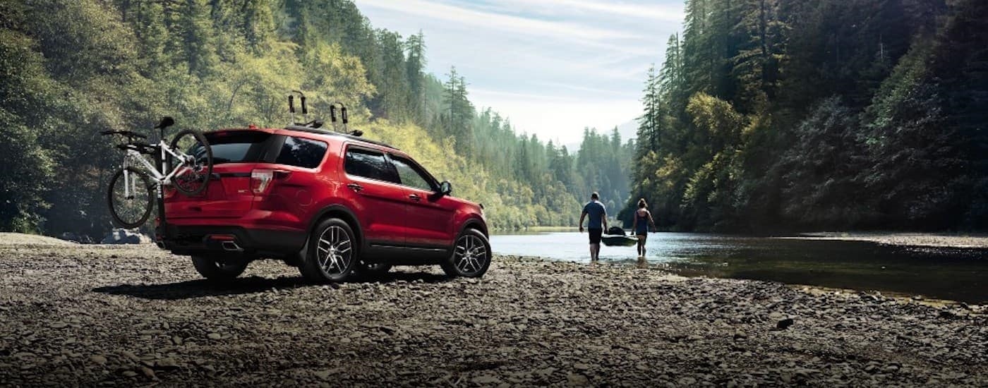 A red 2016 Ford Explorer is shown parked on a river bank.
