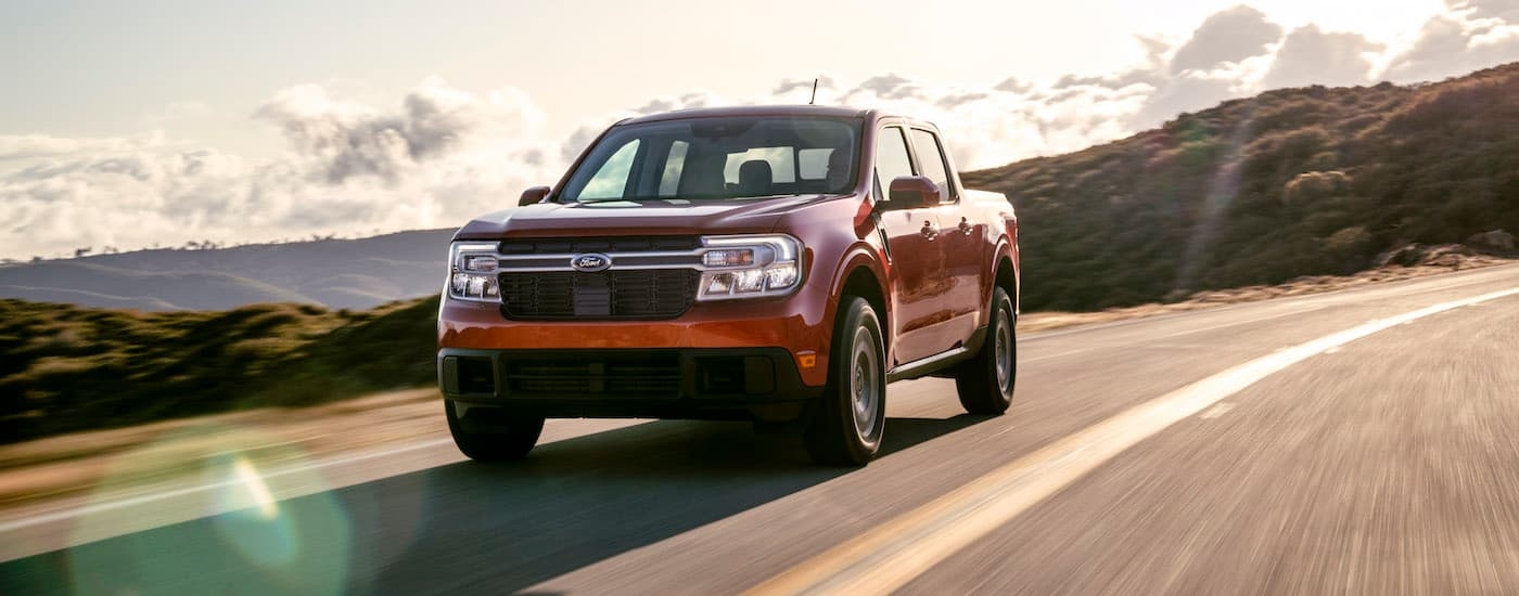 A red 2022 Ford Maverick Lariat is shown driving on a highway after leaving a Rhinebeck Ford dealer.