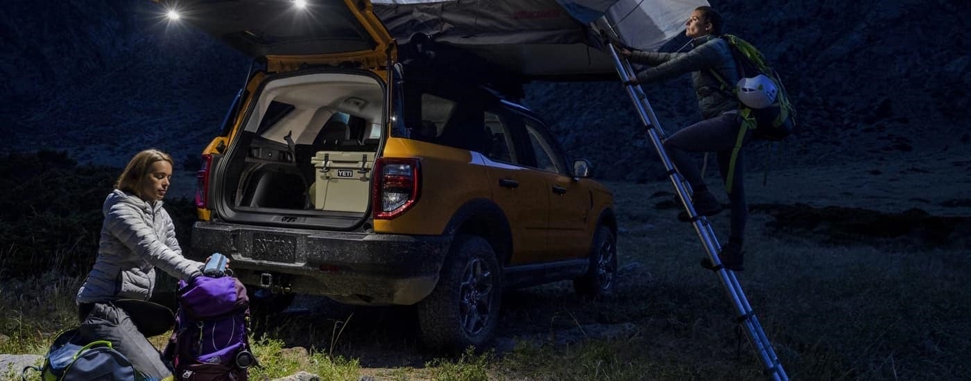 A yellow 2022 Ford Bronco Sport is shown parked at a remote campsite at night.