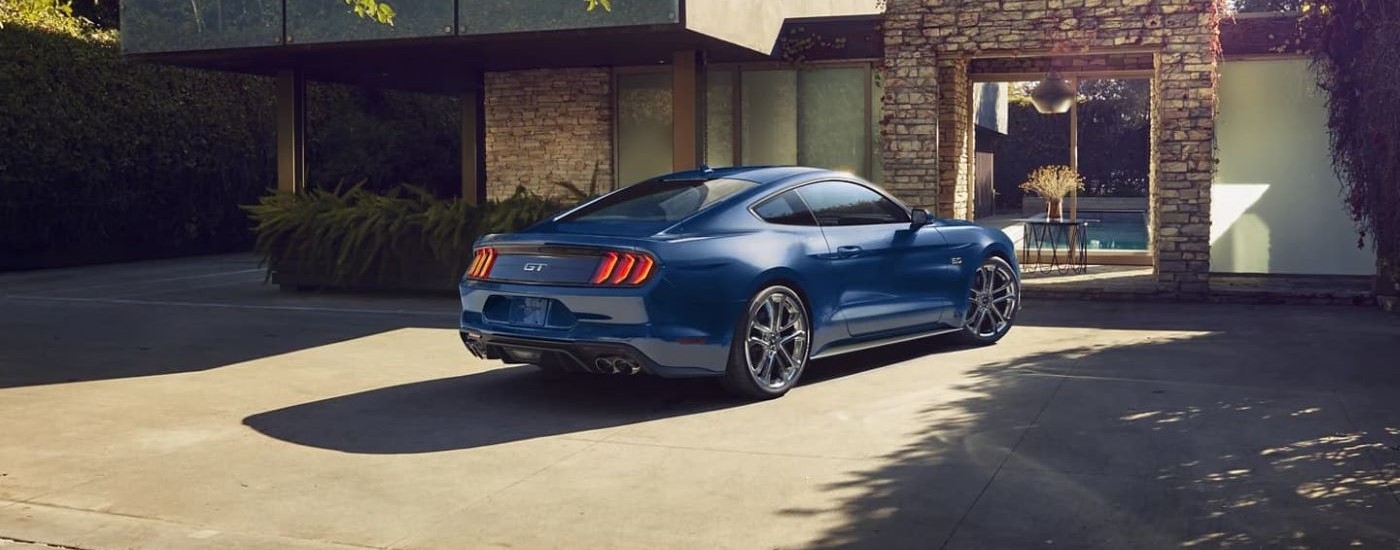 A blue 2022 Ford Mustang is shown from the rear in a driveway after leaving a Kingston Ford dealer.