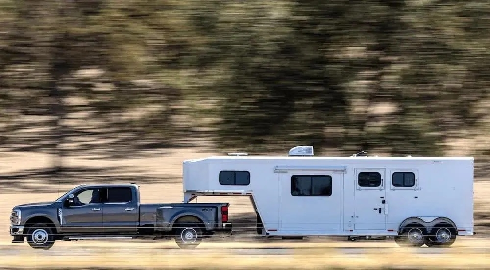 A grey 2023 Ford F-350 is shown from side towing a trailer.