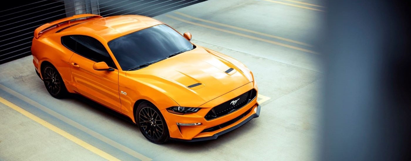 An orange 2020 Ford Mustang GT is from a high angle in a parking garage.
