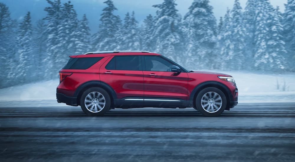 A red 2023 Ford Explorer Limited is shown from the side on a snowy road after leaving a Hudson Ford dealer.