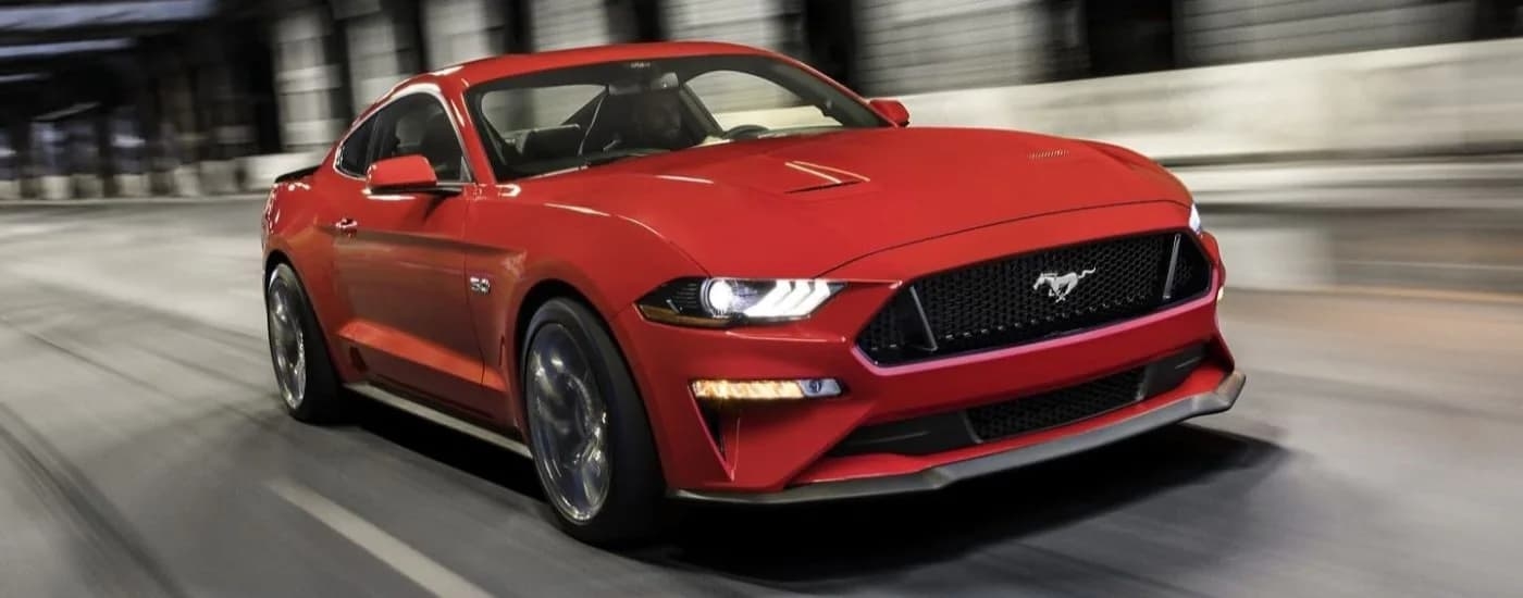 A red 2023 Ford Mustang GT is shown driving through a tunnel.