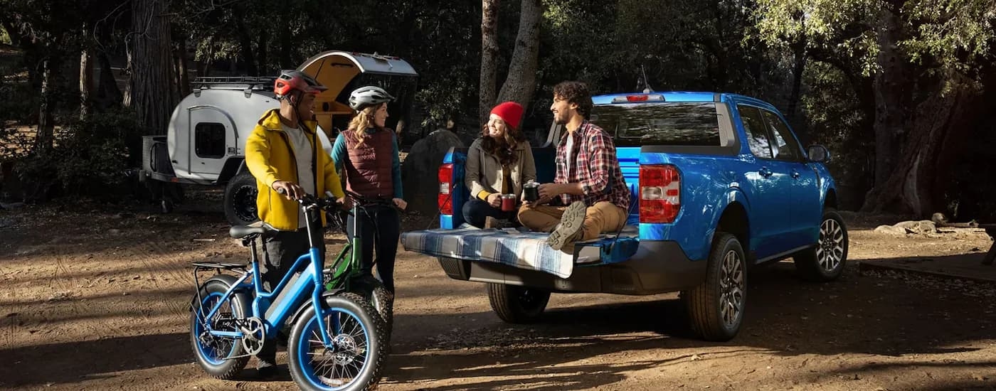 A group of friends are shown near the bed of a blue 2022 Ford Maverick.