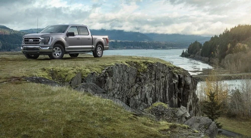 A silver 2021 used Ford F-150 for sale is shown parked near a lake.