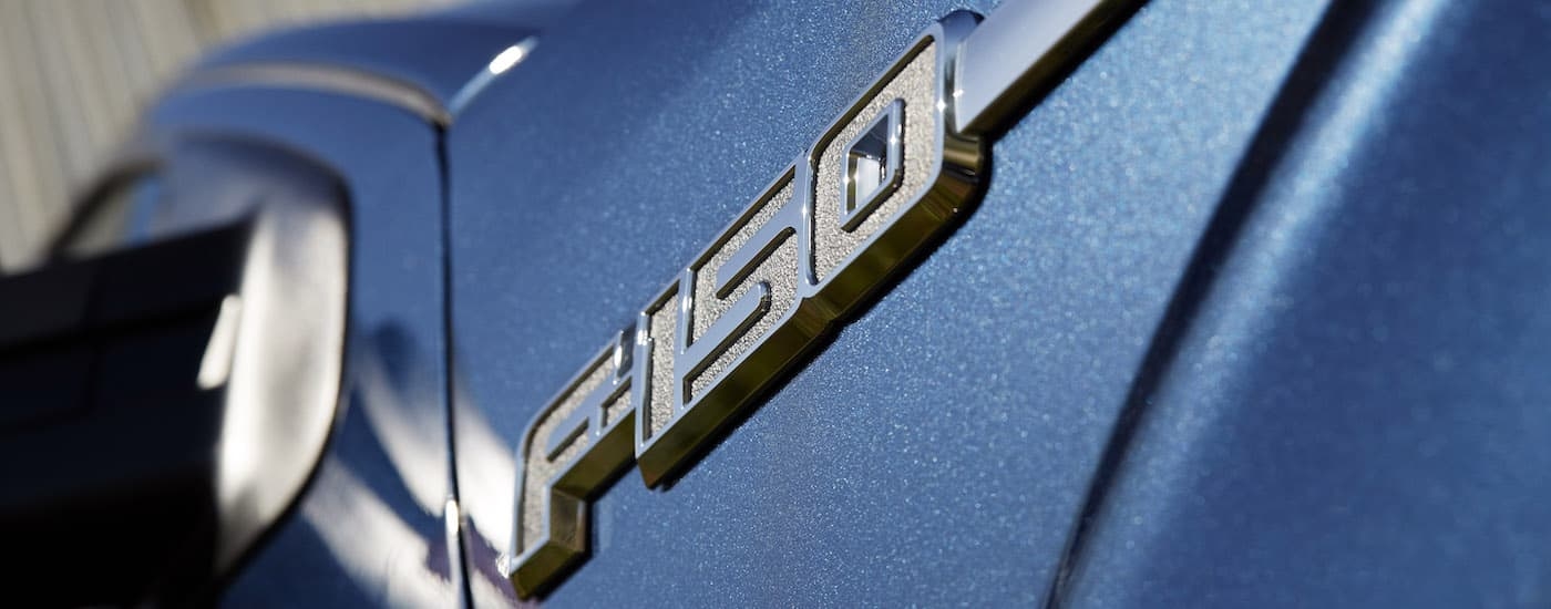 A close up shows the badge on a blue 2014 Ford F-150 XLT.