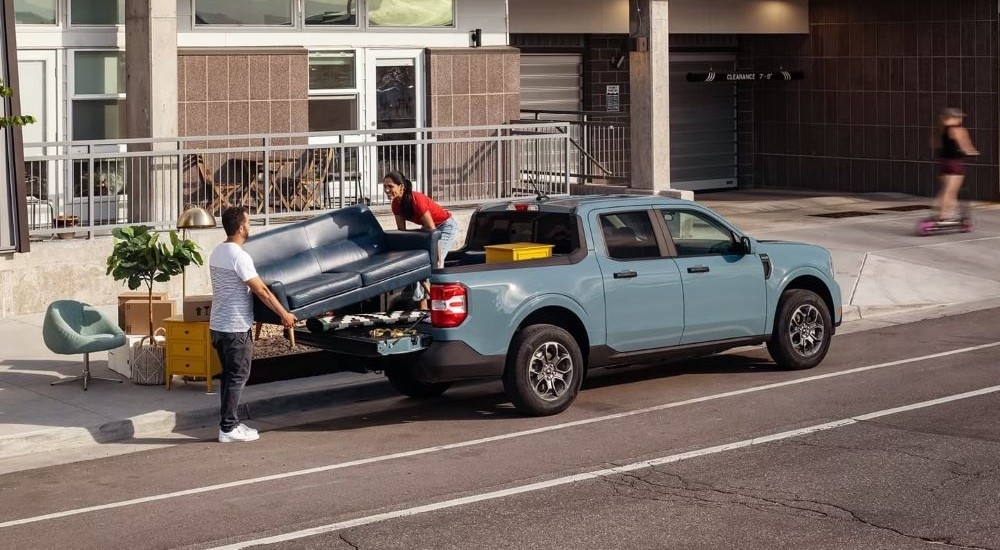 A couple is shown loading a couch onto a 2022 Ford Maverick.