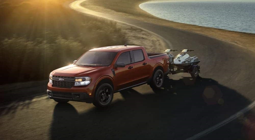 An orange 2022 Ford Maverick is shown from the side towing a trailer.