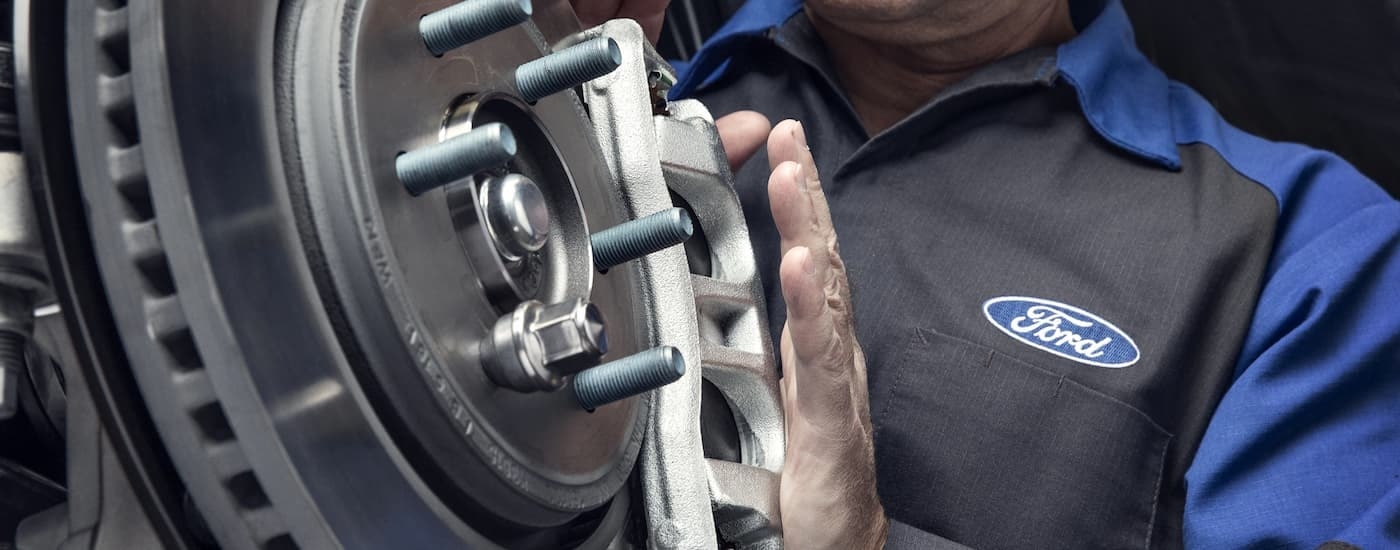 A Ford mechanic is shown inspecting a vehicle's brakes.