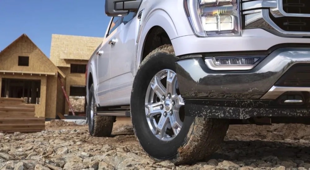 A close up shows the wheel on a silver 2023 Ford F-150 at a construction site.