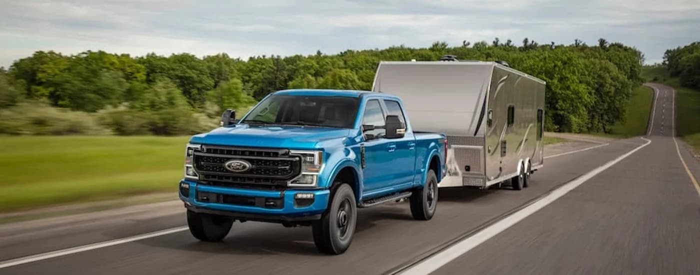 A blue 2020 Ford F-250 Tremor is shown from the front while towing a camper.