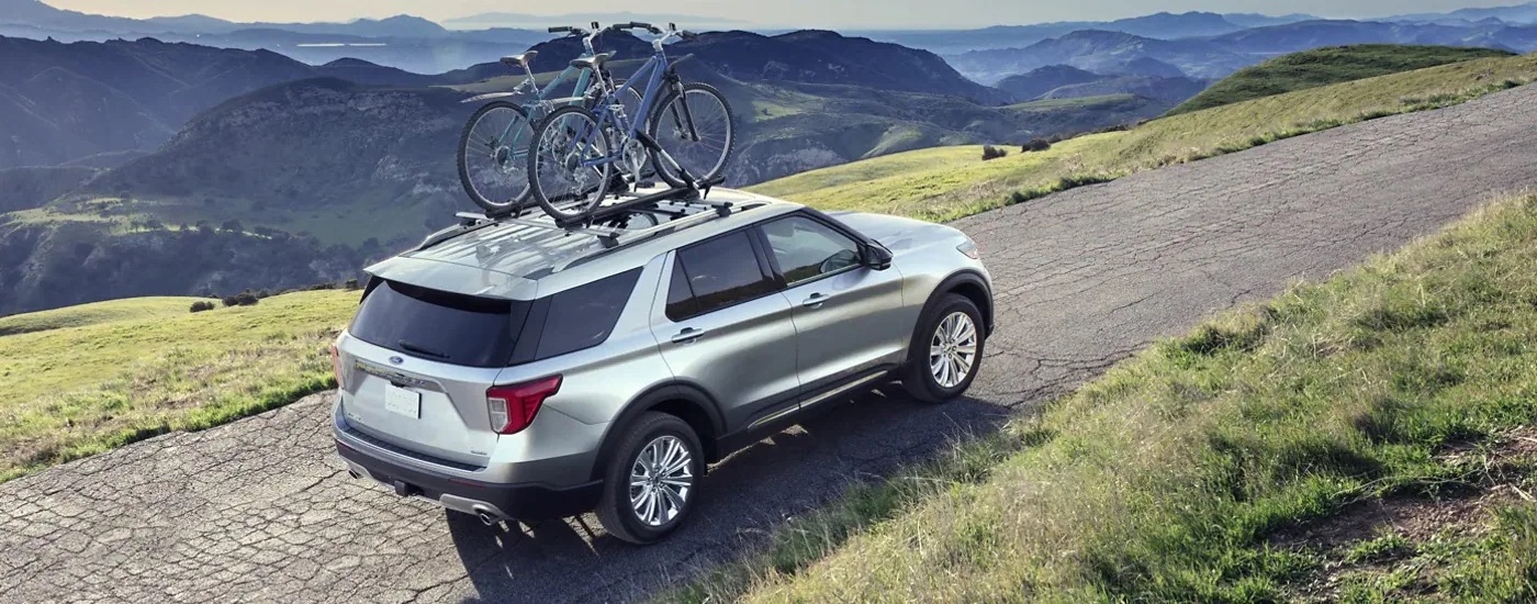 A silver 2022 Ford Explorer is shown from a rear angle driving on a dirt road.