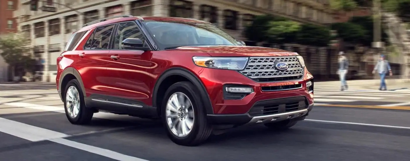 A red 2020 Ford Explorer is shown driving on a city street.