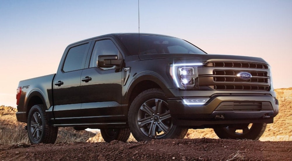 A black 2022 Ford F-150 Lariat is shown parked on a dirt pile.