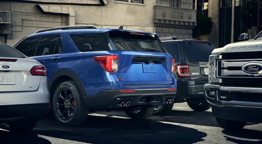 A blue 2023 Ford Explorer ST is shown from the rear while parked in a spot on the side of a city street.