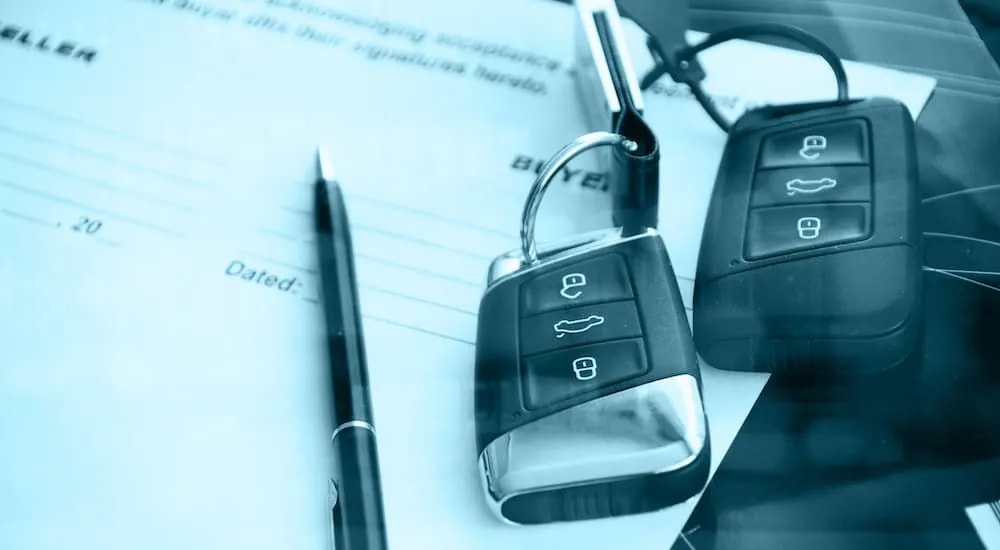 A close up shows car keys on top or paperwork.