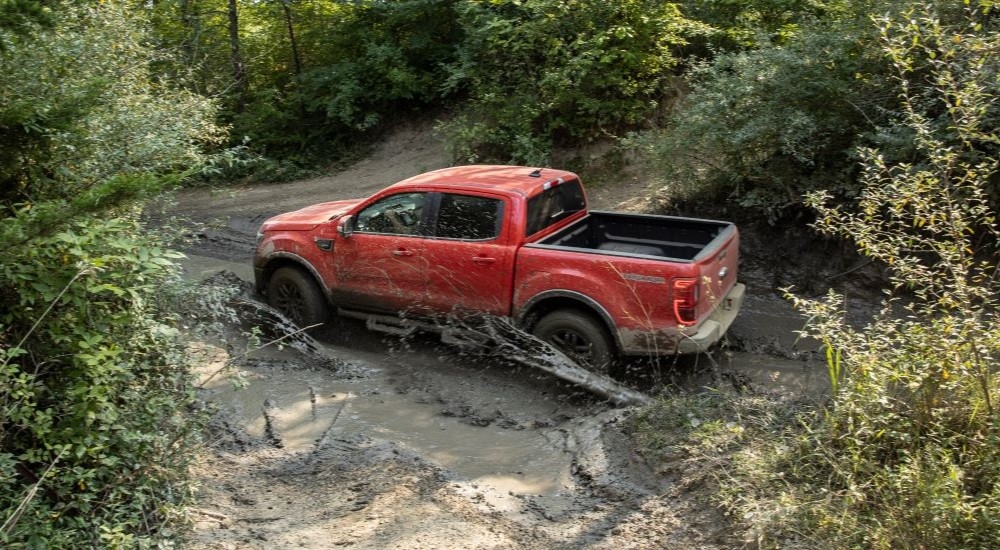 A red 2021 Ford Ranger Tremor Lariat is shown driving through mud after leaving a New Paltz Ford dealer.