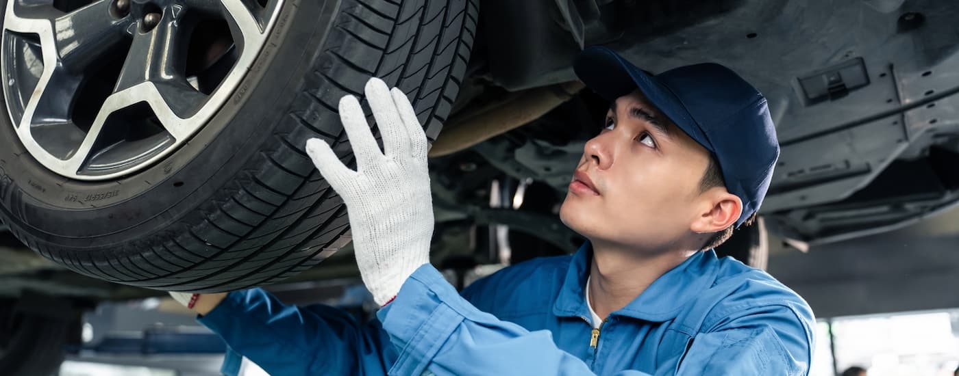 A mechanic is shown inspecting a tire that's on a lift.