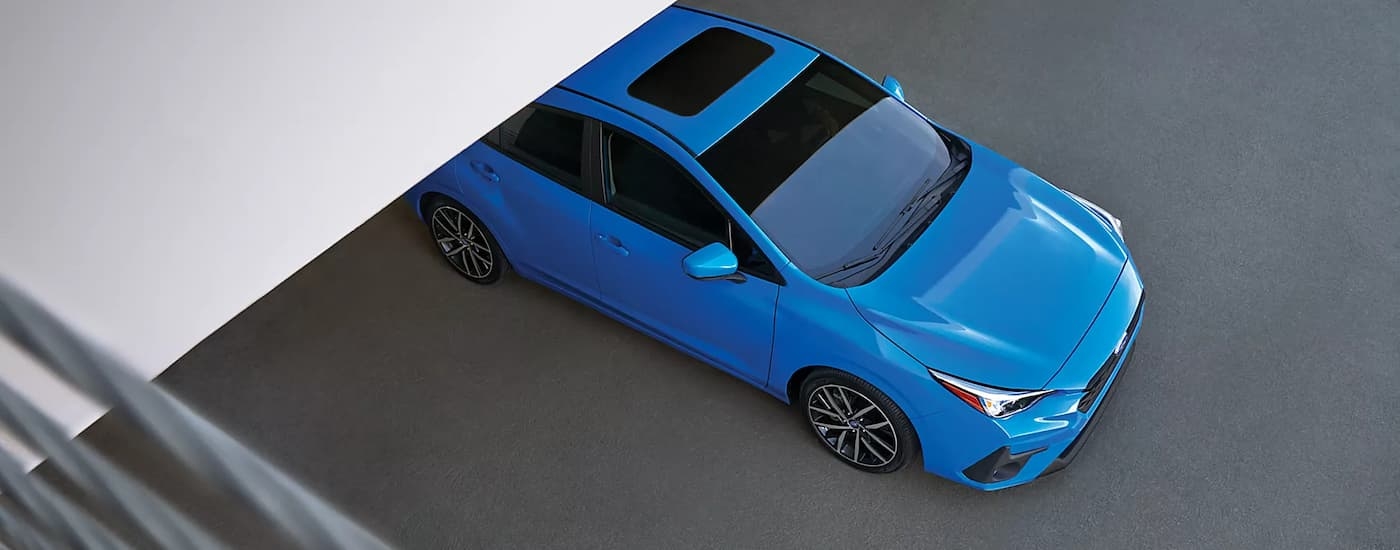 A blue 2024 Subaru Impreza is shown from above leaving a repair shop after a Subaru service.