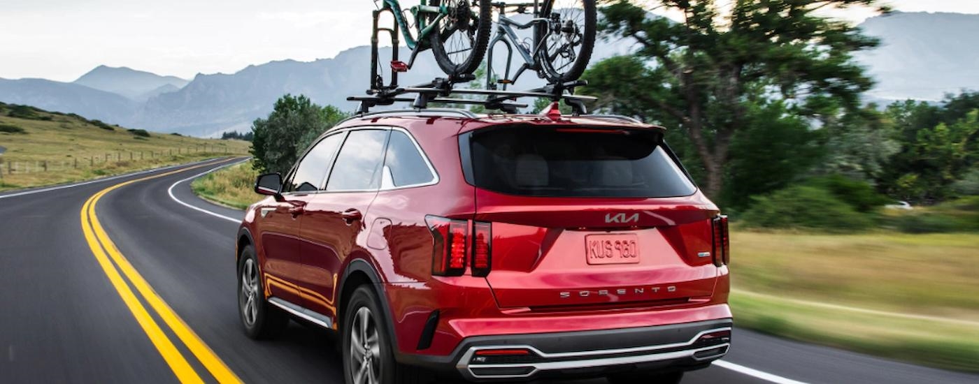 A red 2022 Kia Sorento Hybrid is shown from a rear angle with bikes on the roof.