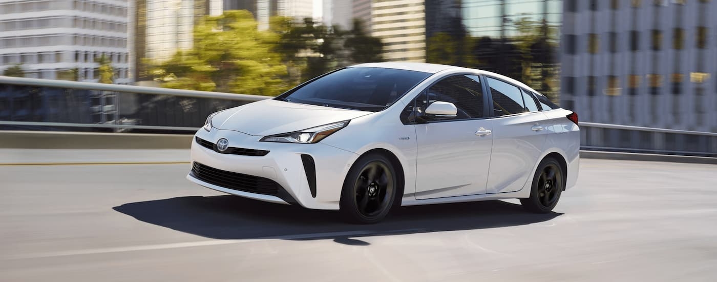 A white 2020 Toyota Prius is shown from the side driving on a highway.