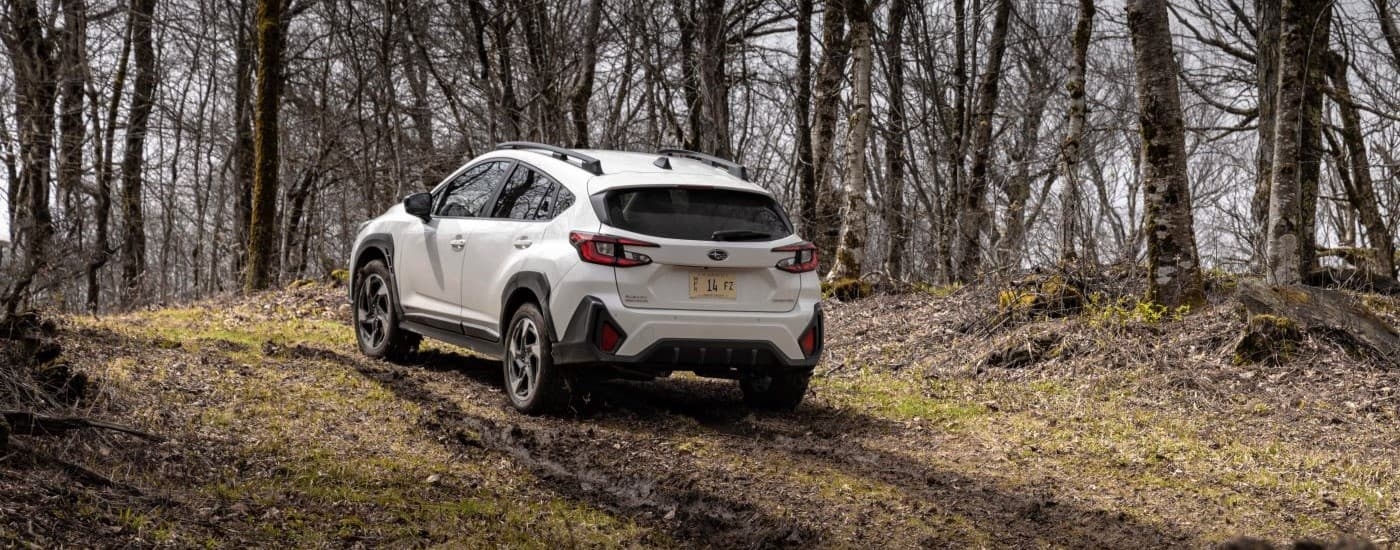 A white 2024 Subaru Crosstrek Limited is shown driving up a trail after leaving a car dealership.
