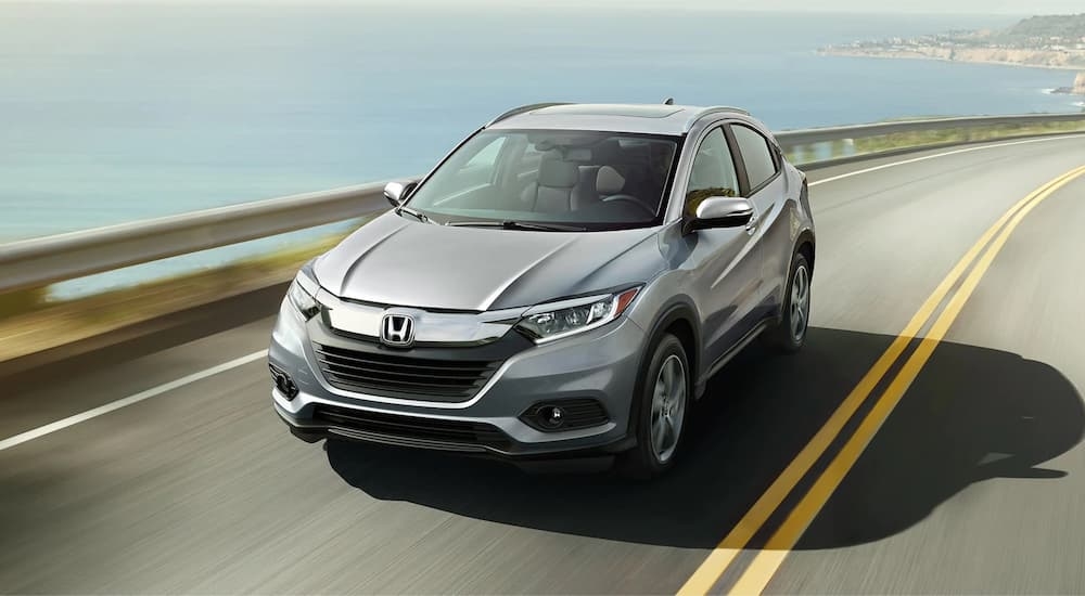 A silver 2022 Honda HR-V driving on a winding coastal road towards a used SUV dealer.