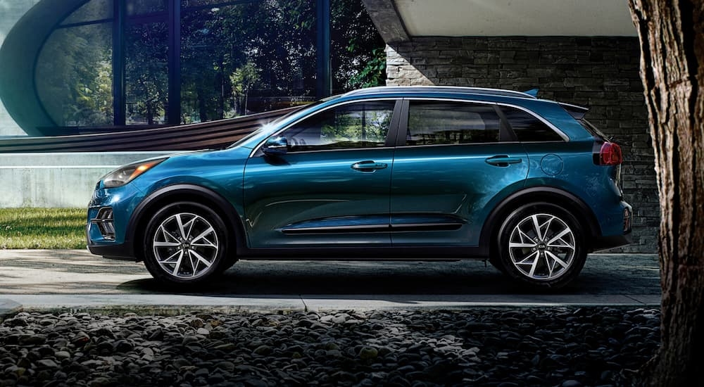 A blue 2020 Kia Niro parked in front of a modern home.