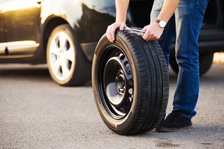 Mechanic rolling a tire into a car shop