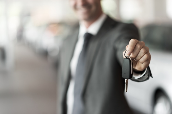 Man in a suit holding out a car key
