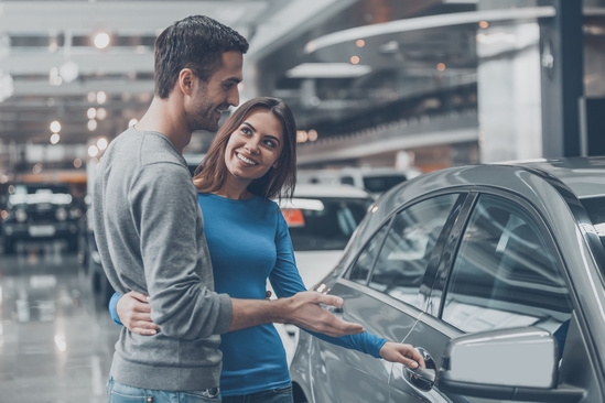A couple checking out cars at a dealership together