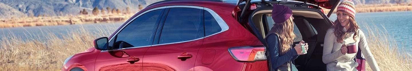 Two woman sitting on the back of a red Ford Escape