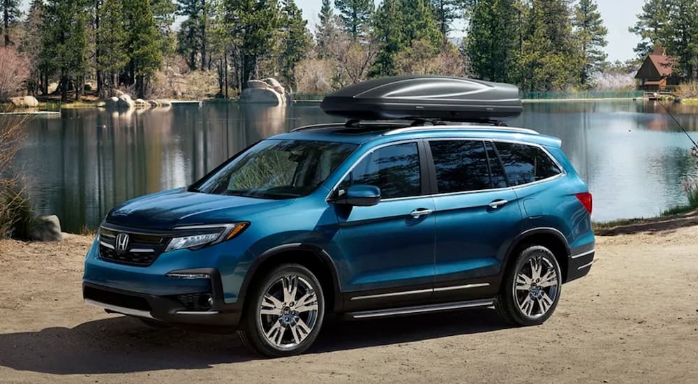 A blue 2021 Honda Pilot parked next to a lake.