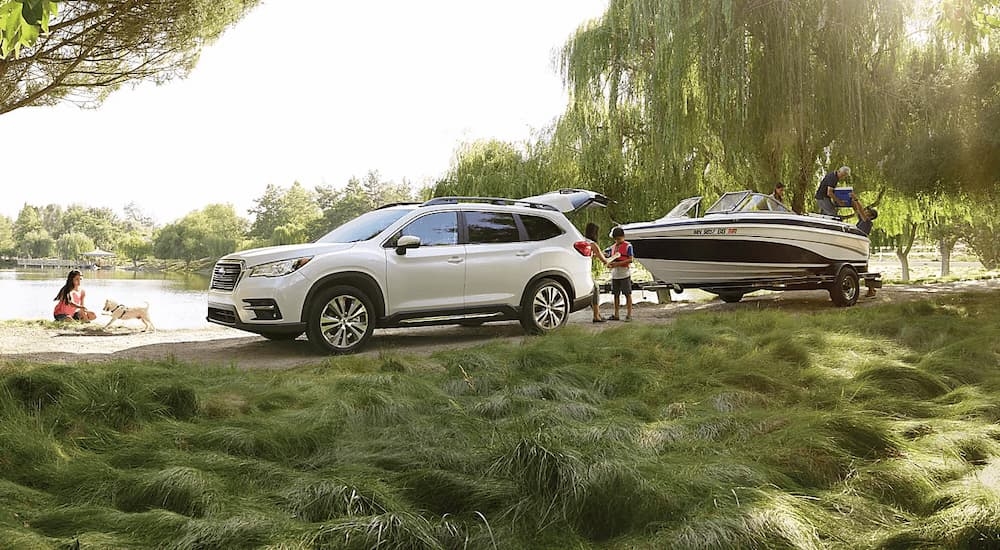 A white 2022 Subaru Ascent towing a small fishing boat to a boat launch.